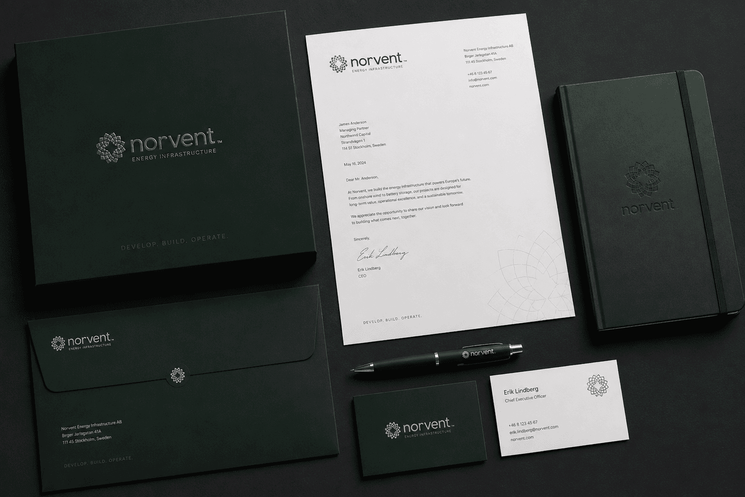 Norvent stationery laid out on black — a presentation box, letterhead, envelope, notebook, pen and business cards in forest green with a silver rosette